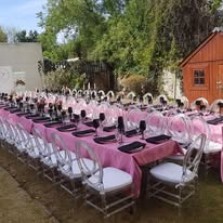 Long tables dressed in pink with ghost chairs in the garden