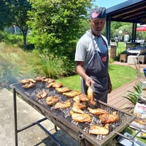 Our chef grilling chicken over the coals in the garden
