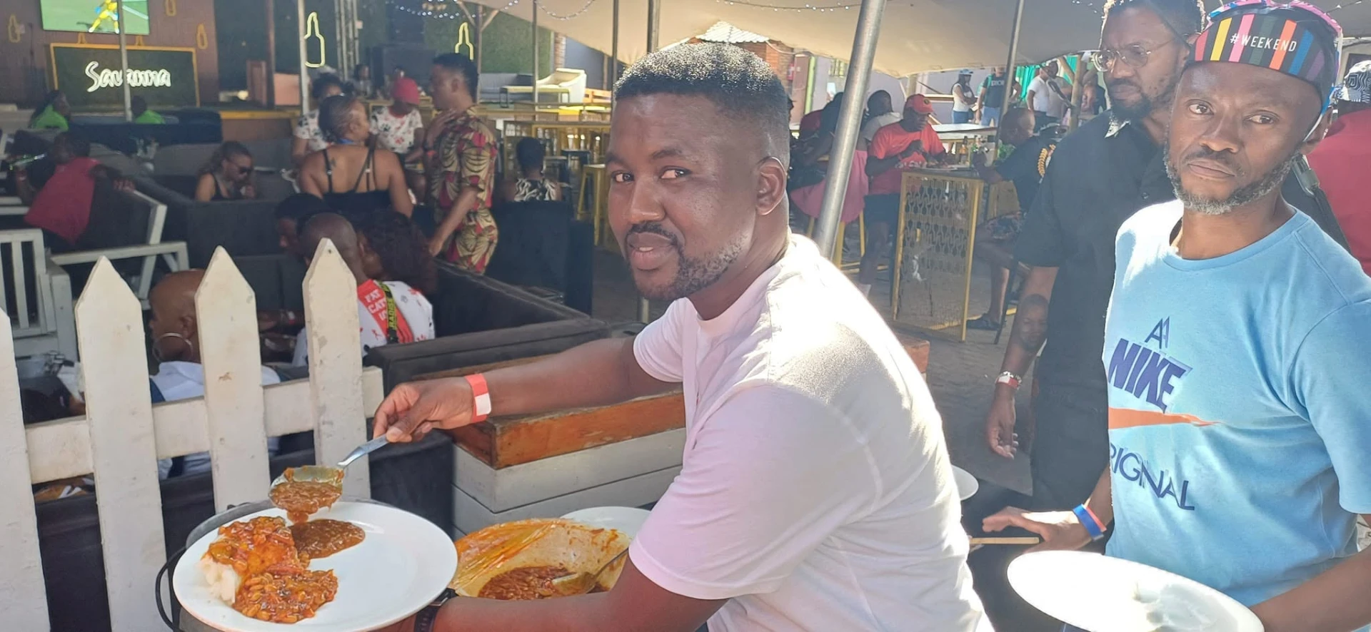 Serving pap and stew at a busy tented shisanyama event
