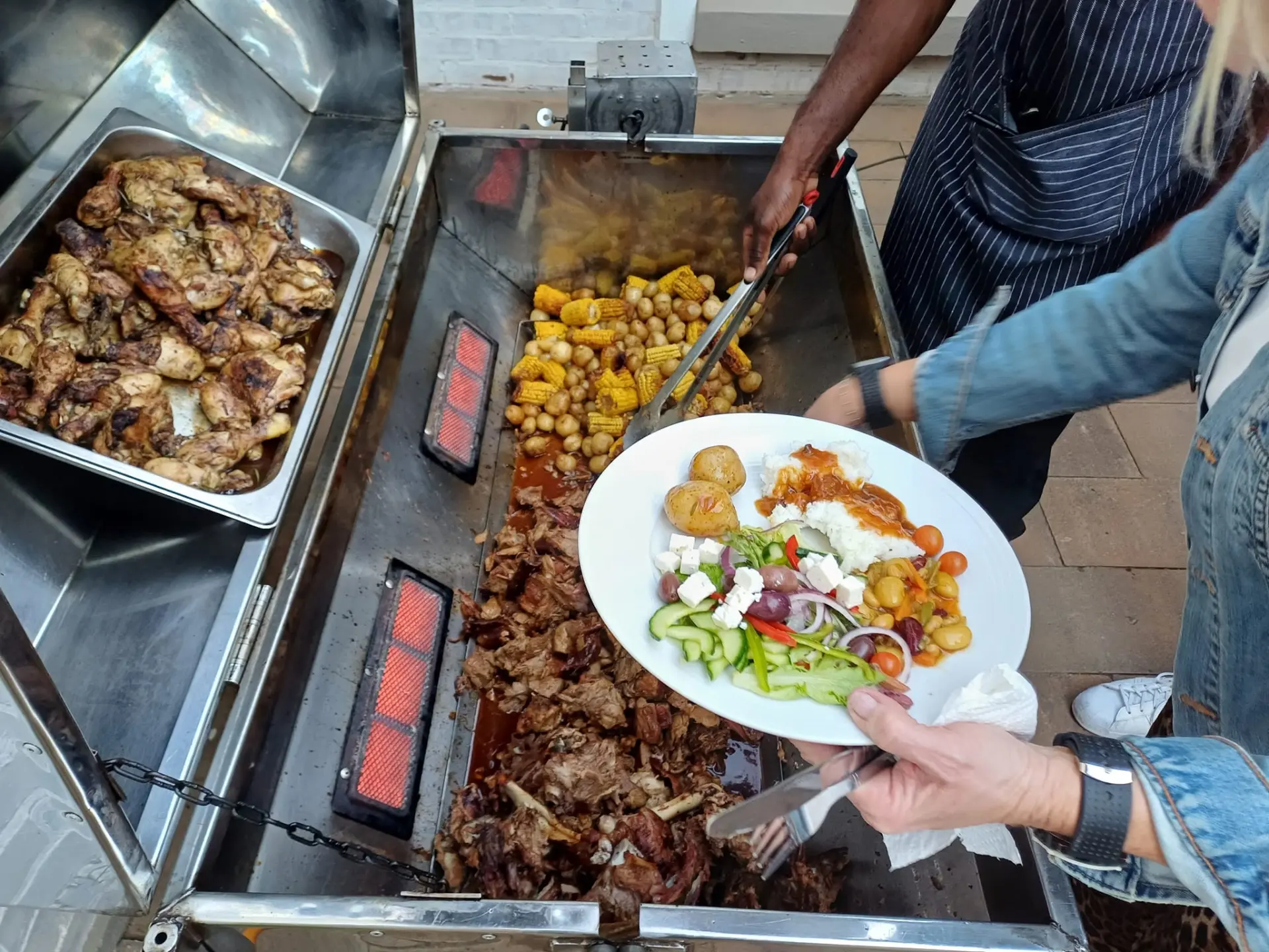 Hot roast station with meat, corn, potatoes and a loaded plate