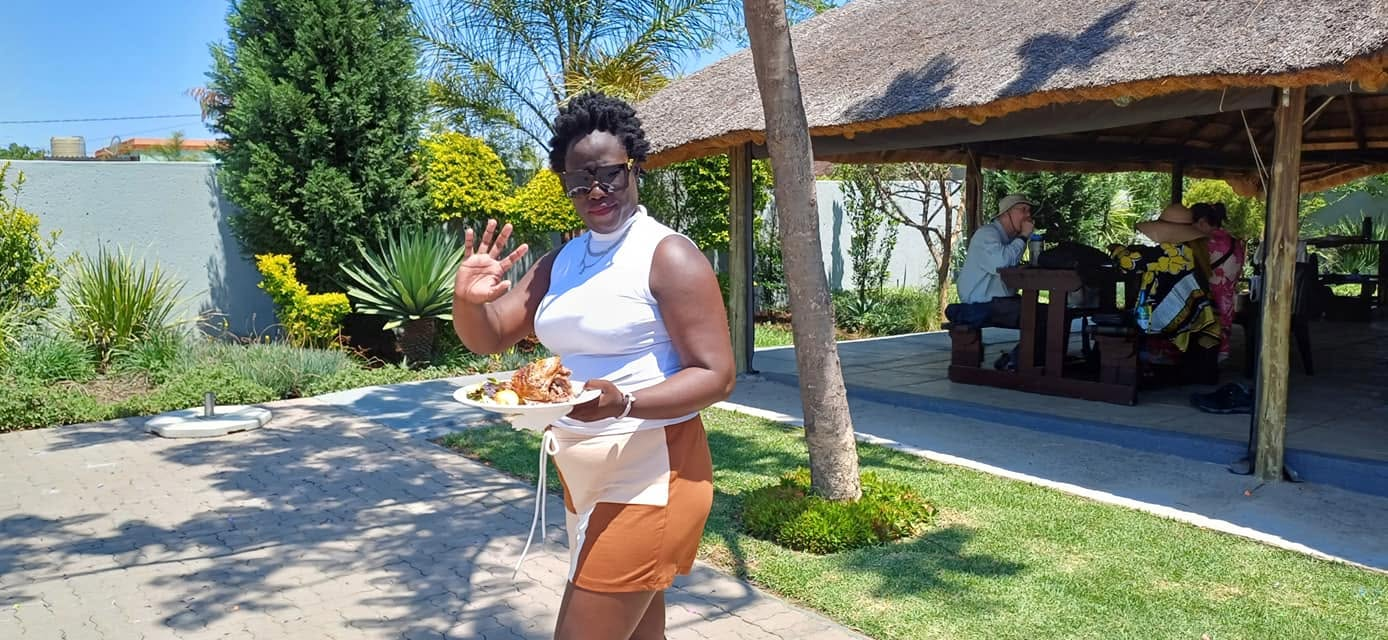 Guest waving with a plate of food in the garden