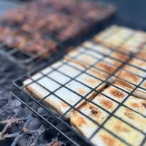 Meat and flatbread cooking on a wire grill over coals